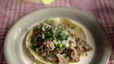 Beyaz ve kırmızı kareli masa örtüsünün üzerinde sığır eti barbacoa taco.