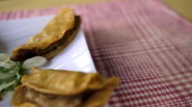 Meksika sepeti tacoları ve beyaz tabakta soğan dilimleri.