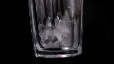 Yavaşça buz küplerini boş bir bardağa atıyorlar.