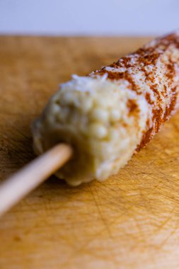 Acı biberli Meksika mısırı ve rendelenmiş peynir ahşap bir yüzeyde.