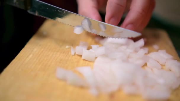Mãos lentamente cortando uma cebola na tábua de corte de madeira — Vídeo de Stock