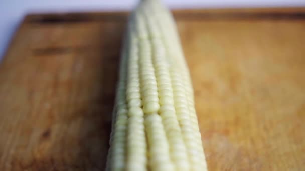 Gekookte en gespietste maïs op een houten snijplank — Stockvideo