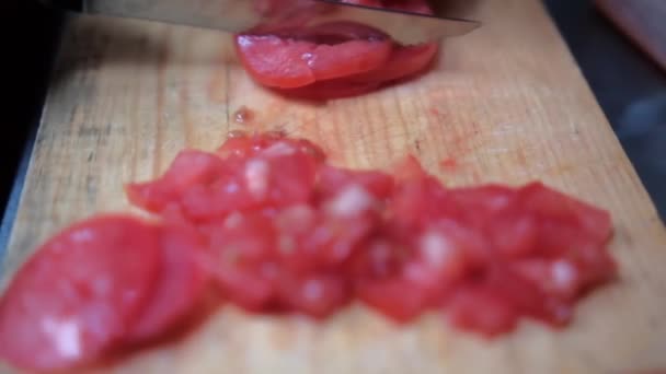 Mãos lentamente cortando um tomate na tábua de corte de madeira — Vídeo de Stock