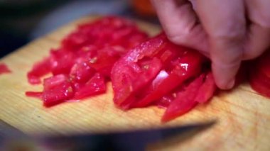 Eller yavaşça bir domatesi tahta kesme tahtasıyla doğruyor.