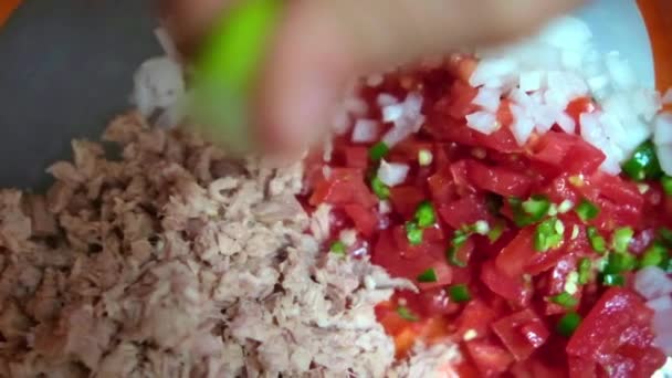 Hand squeezing lime onto chopped tuna and Mexican pico de gallo — Stock Video