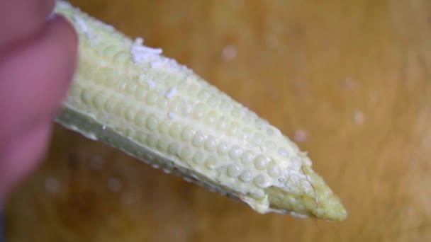 Рука посыпать сыром кукурузу над деревянной доской — стоковое видео