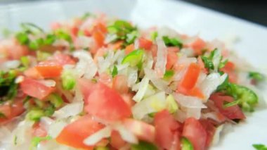 Beyaz tabakta doğranmış domates, soğan ve kırmızı biber.