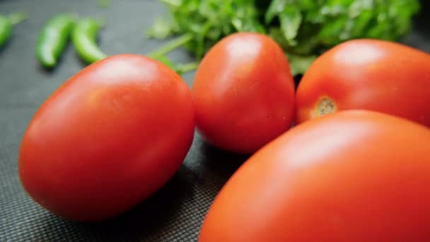 Tomates y cilantro sobre una mesa azul oscuro — Vídeos de Stock