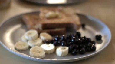 Kadın eli yavaşça yumurtalı ekmeğin üzerine muz serpti.