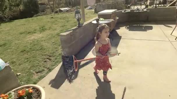 Imádnivaló kislány játszik egy seprűvel a nagy kertben — Stock videók