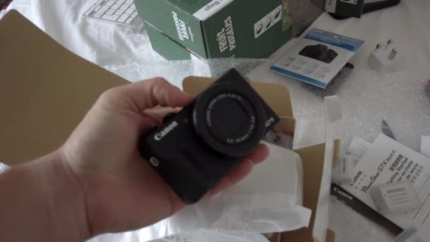 Mannelijke hand die Canon camera boven het open pakket houdt — Stockvideo