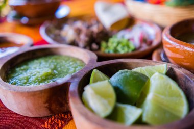 Limon dilimleri, yeşil sos ve renkli masa örtüsü üzerinde kuzu çorbası.