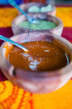 Renkli masa örtüsünün üzerinde tahtadan yapılmış sıcak soslar ve limon dilimleri.