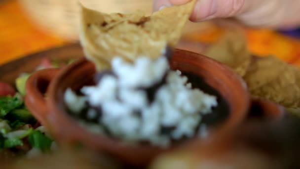 Hand taucht Tortilla Chip in Schüssel mit gebackenen Bohnen mit Käse — Stockvideo