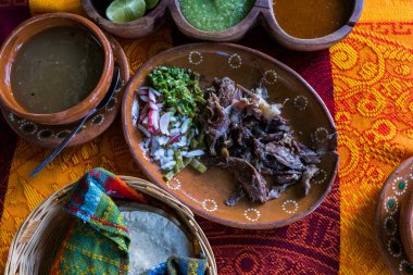 Meksika usulü kuzu eti, acı sos ve renkli masa örtüsü üzerine tortilla.