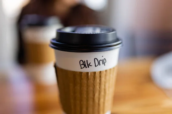 White and brown disposable paper coffee cup with blurry background