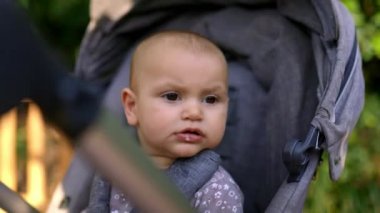 Gri bebek arabasındaki sevimli ve endişeli bebek. Geçmişi bulanık.