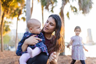 Parlak günbatımı olan bir bebeği arka plan olarak tutan güzel bir kadın manzarası
