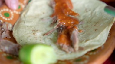 Meksika usulü kuzu etli tako ile kilden bir tabak tutarken yakın plan.