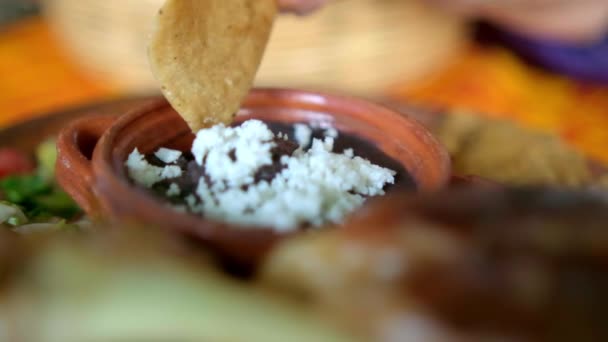 Hand dipping tortilla chip into bowl of refried beans with cheese — Stock Video