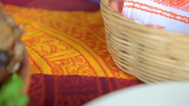 Roasted meat with vegetables and palm basket on colorful tablecloth — Stock Video