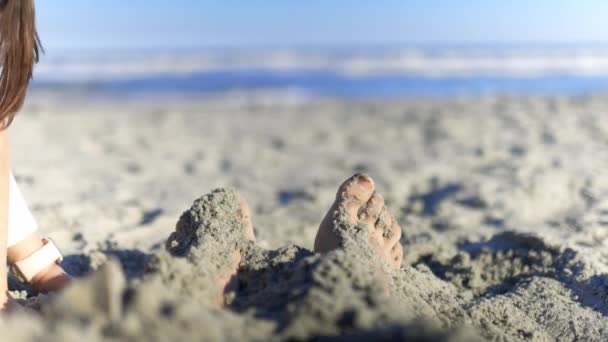 Entzückendes kleines Mädchen bedeckt erwachsene Füße mit Sand am Strand — Stockvideo