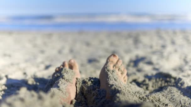 Adorable little girl kicking sand at adult feet on the beach — Stock Video