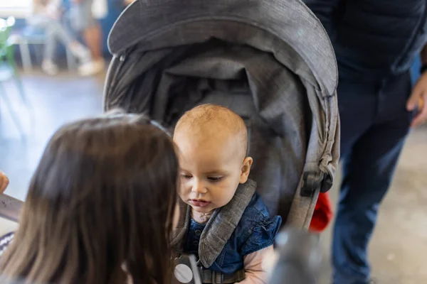 Förtjusande glad bebis i grå barnvagn i restaurang — Stockfoto