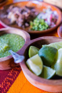 Kırmızı ve turuncu masa örtüsü üzerinde limon dilimleri ve acı sos.