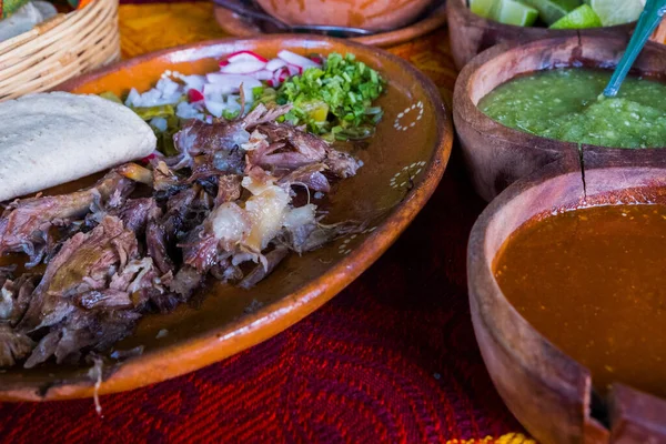 Meksykańskie mięso jagnięce posiekane, gorące sosy i bulion na kolorowym obrusie — Zdjęcie stockowe