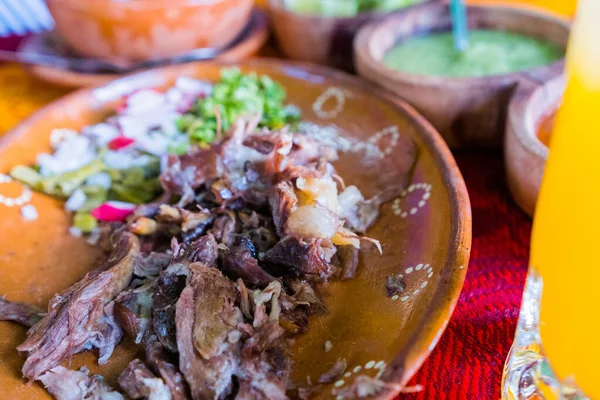 Mexican chopped lamb meat, hot sauces, and lime slices on colorful tablecloth — Stock Photo, Image