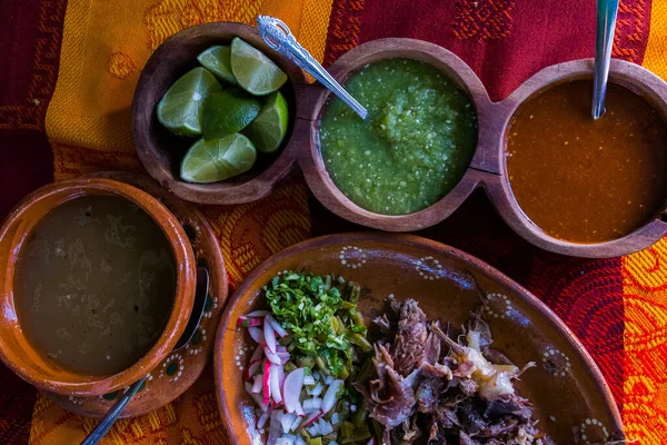 Mexican chopped lamb meat, hot sauces, and broth on colorful tablecloth — Stock Photo, Image