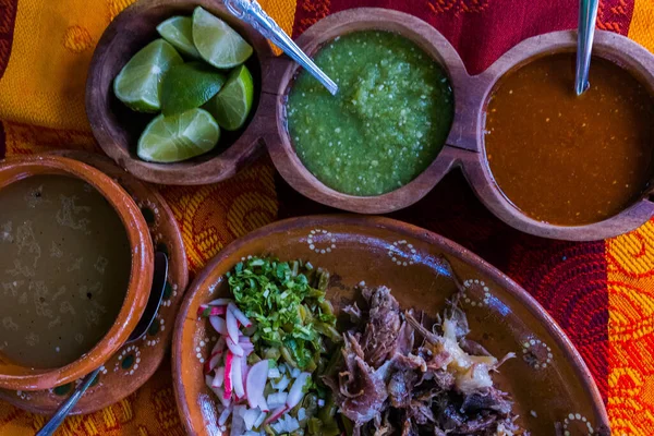 Mexican chopped lamb meat, hot sauces, and broth on colorful tablecloth — Stock Photo, Image