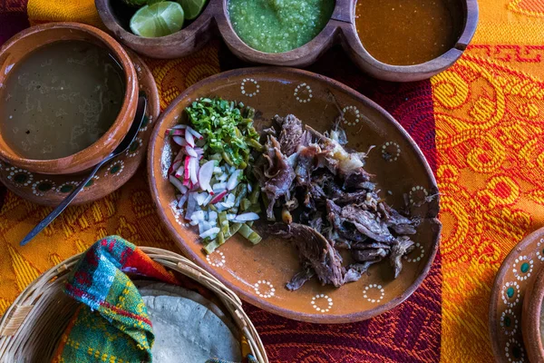 Mexican chopped lamb meat, hot sauces, and tortillas on colorful tablecloth — Stock Photo, Image