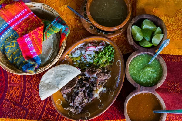 Mexican chopped lamb meat, hot sauces, and tortillas on colorful tablecloth — Stock Photo, Image