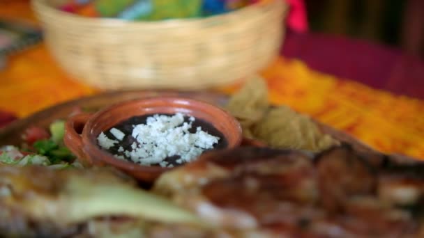 Roasted meat with vegetables and refried beans on colorful tablecloth — Stock Video