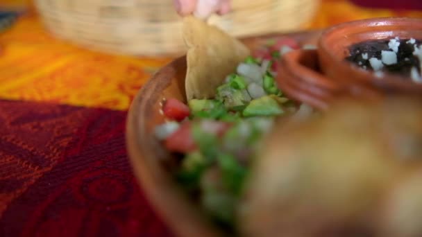 Mano sumergiendo la tortilla chip en el plato del pico de gallo tradicional — Vídeos de Stock