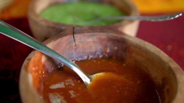 Boluri de lemn de sosuri roșii și verzi fierbinți deasupra feței de masă colorate — Videoclip de stoc