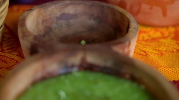 Cuencos de madera de salsas rojas y verdes calientes por encima de mantel colorido — Vídeo de stock