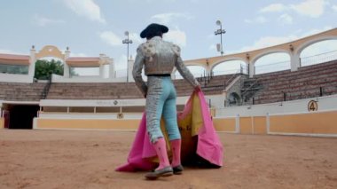 Boğa güreşçisi pelerinini yavaşça sallıyor.