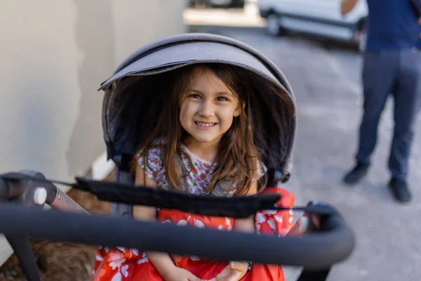 Счастливая маленькая девочка в серой коляске с размытым фоном — стоковое фото
