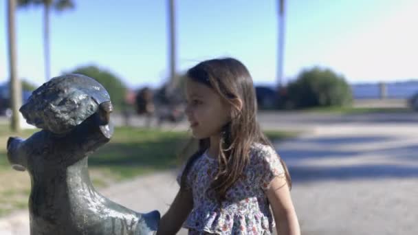 公園で子供の像の頭を掃除する愛らしい若い女の子 — ストック動画