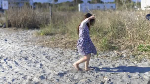 Adorable niña jugando en la arena gris con hierba seca como fondo — Vídeo de stock