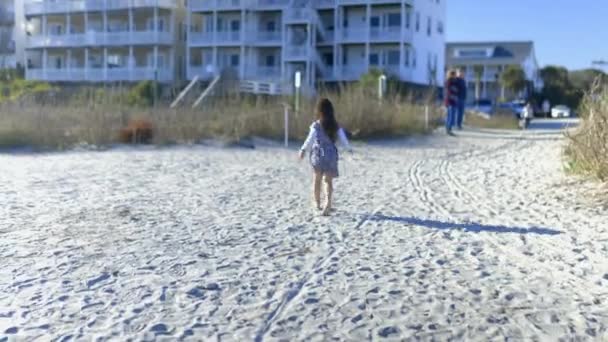 Adorable niña corriendo sobre arena rodeada de hierba seca — Vídeo de stock