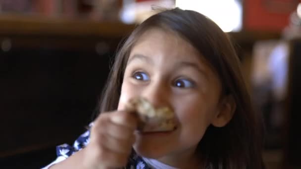 Adorabile bambina seduta al tavolo di un ristorante che mangia fetta di pizza — Video Stock