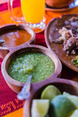 Kırmızı ve turuncu masa örtüsü üzerinde limon dilimleri ve acı sos.