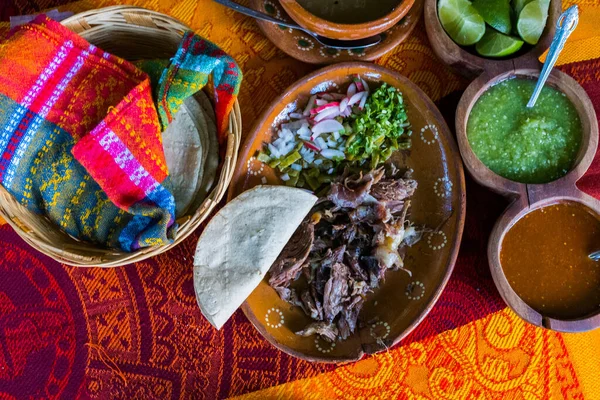 Mexican chopped lamb meat, hot sauces, and tortillas on colorful tablecloth — Stock Photo, Image