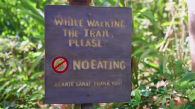 Ahşap tabela, insanların arka planda bitkilerle yemek yememelerini istiyor.