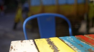 Renkli kırsal masa ve arka planda sarı kargo motosikleti olan sandalye.