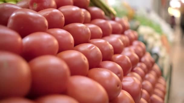 Pile of tomatoes on stand with more vegetables as background — Stock Video